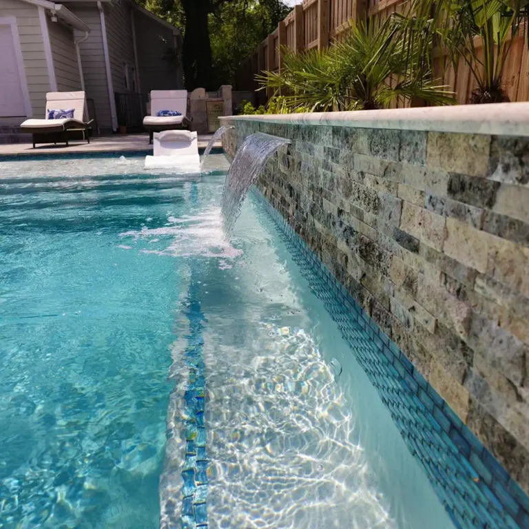 Pool with a sheer water feature flowing from a stacked stone wall